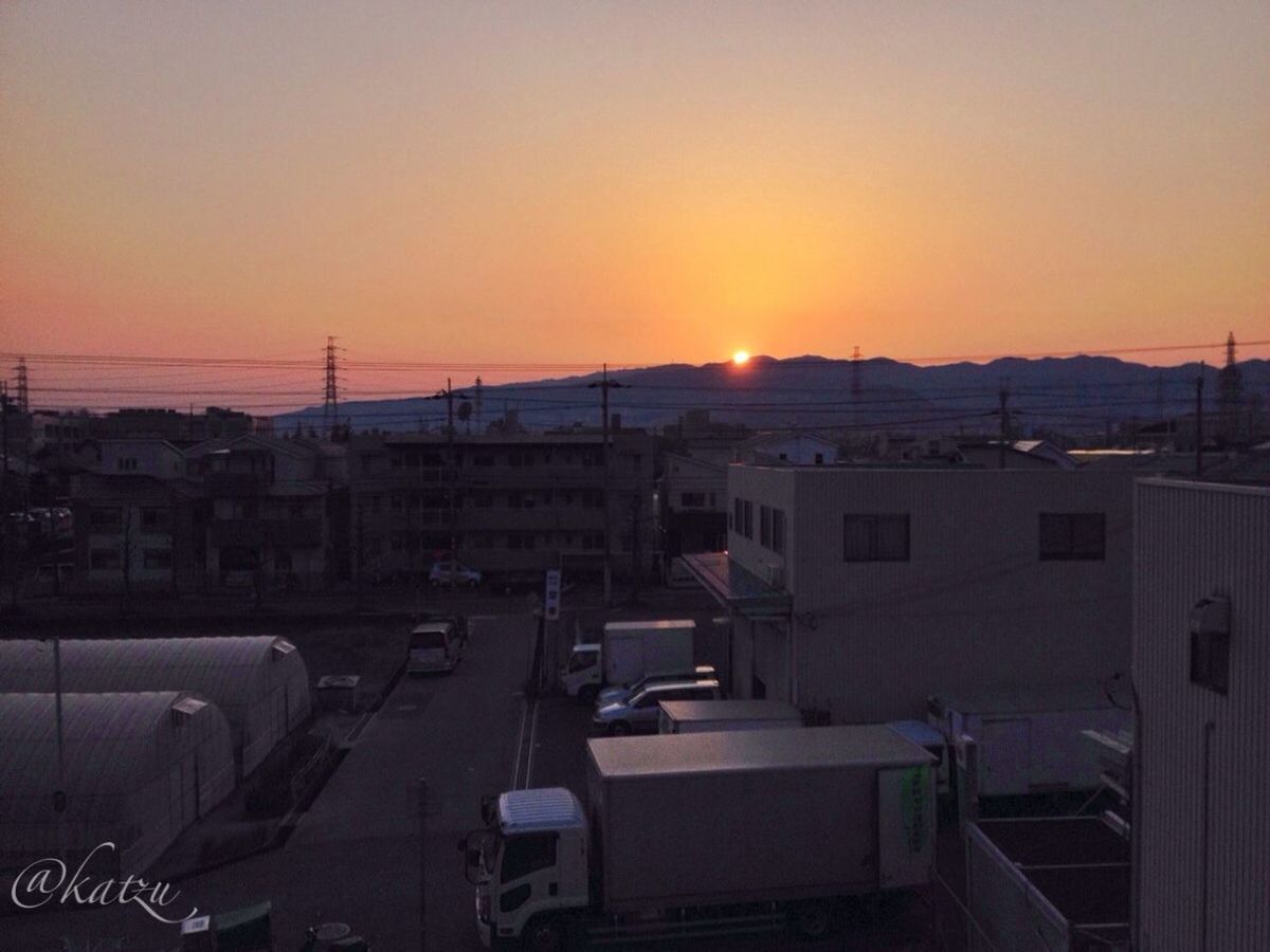 sunset, transportation, building exterior, architecture, mode of transport, orange color, car, built structure, land vehicle, city, sun, clear sky, sky, copy space, road, sunlight, residential structure, street, outdoors, high angle view