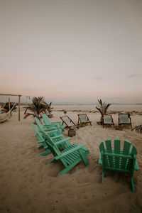 Deck chairs on beach against clear sky