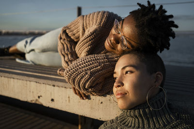 Female friends resting on bench during sunset