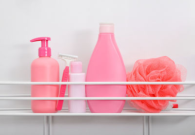 Close-up of pink bottles on shelf against white background