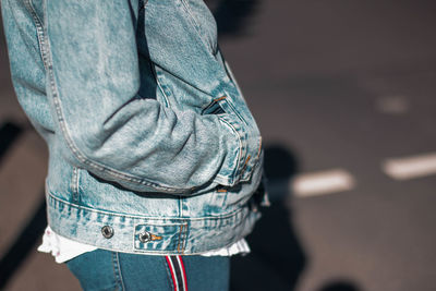 Midsection of woman with hands in pockets standing on road