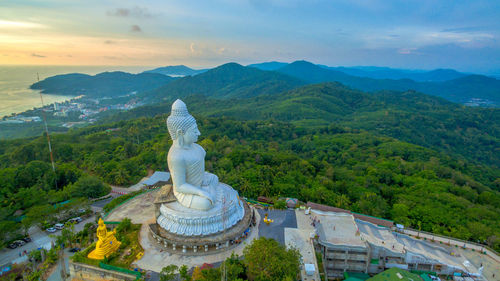 Statue by trees and mountains against sky