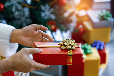 Cropped hands of man holding christmas present at home