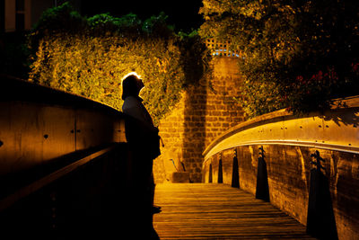 Woman standing on footbridge at night