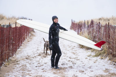 Young woman and dog going winter surfing in snow