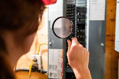 Rear view of woman holding magnifying glass