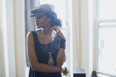 Young woman looking through window at home