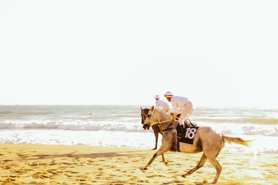 Woman riding horse on beach