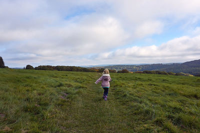 Rear view of woman on field against sky