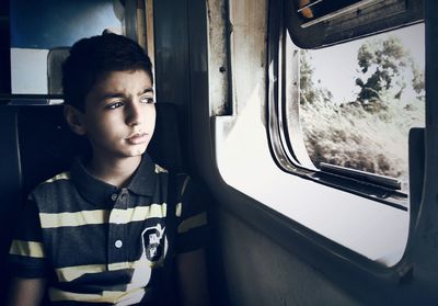 Thoughtful boy looking through train window