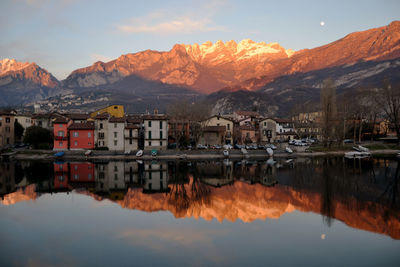 Reflection of buildings in lake against sky during sunset