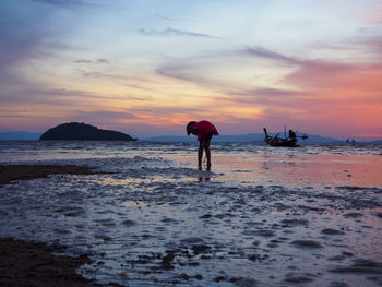 Man standing on beach against sky during sunset
