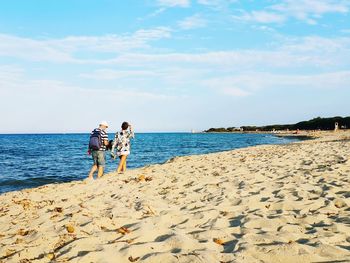 Rear view of people on beach against sky