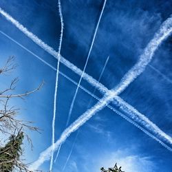 Low angle view of vapor trails against blue sky