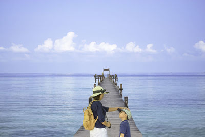 Rear view of men in sea against sky