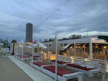 Illuminated buildings by street against sky at dusk