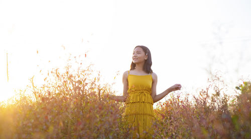 Young woman standing on field against clear sky