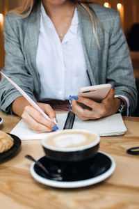 Midsection of woman holding coffee cup on table