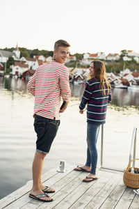 Rear view portrait of man with woman fishing on pier at lake