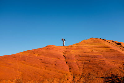 Man on rock formations against clear blue sky