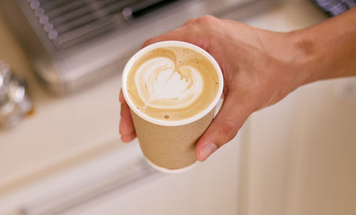 Cropped hand holding coffee on table