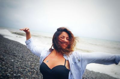 Smiling young woman standing on shore at beach 