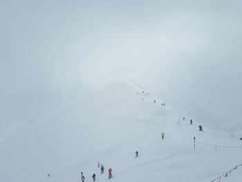 Group of people on snowcapped mountain against sky