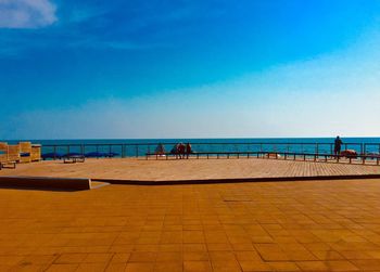 People on promenade against blue sky