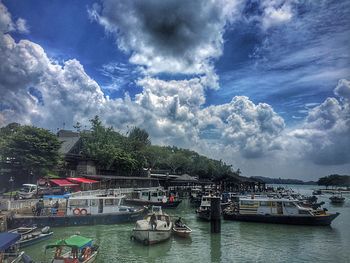 Boats in river against cloudy sky