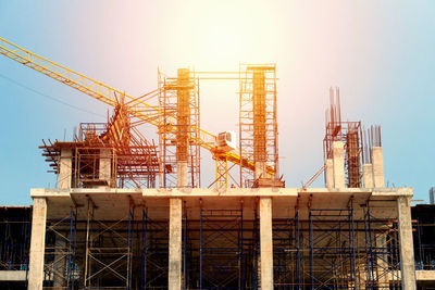 Low angle view of crane at construction site against sky