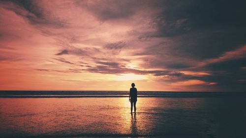 Silhouette man standing on beach against sky during sunset