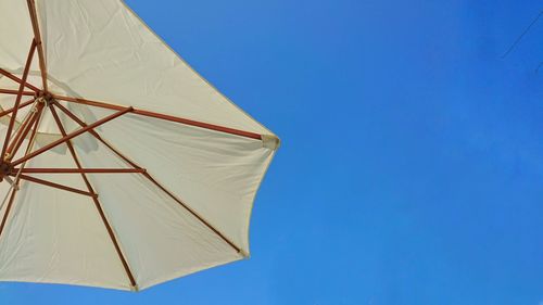 Low angle view of umbrella against clear blue sky