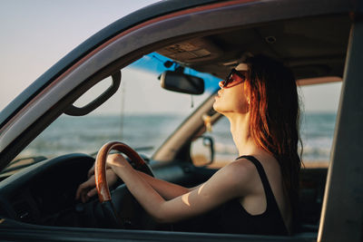 Side view of woman sitting in car