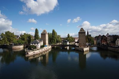 Bridge over river by buildings against sky