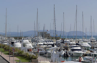 Sailboats moored at harbor against clear sky