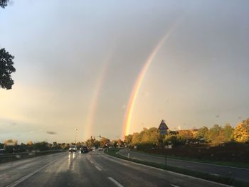 Rainbow over road against sky during sunset