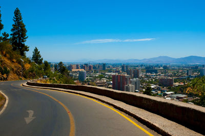 Road amidst buildings against blue sky