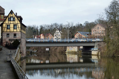 Bridge over river by buildings against sky