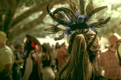 Rear view of woman with headdress standing against people