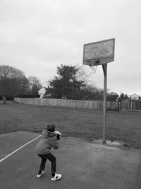 Boy playing with ball on field against sky