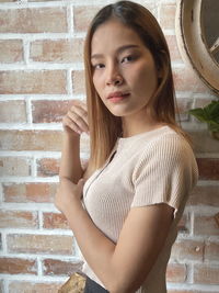 Portrait of woman standing against brick wall