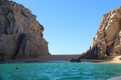 Scenic view of sea and rock formation against clear blue sky