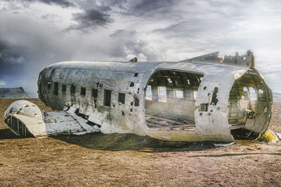 Abandoned airplane on airport runway against sky