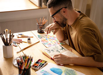 Side view of man using mobile phone while sitting on table