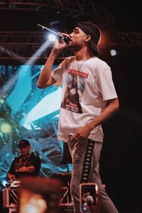 Young man with arms raised standing at music concert