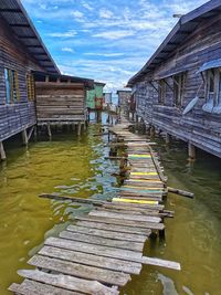 Wooden pier over canal amidst buildings against sky