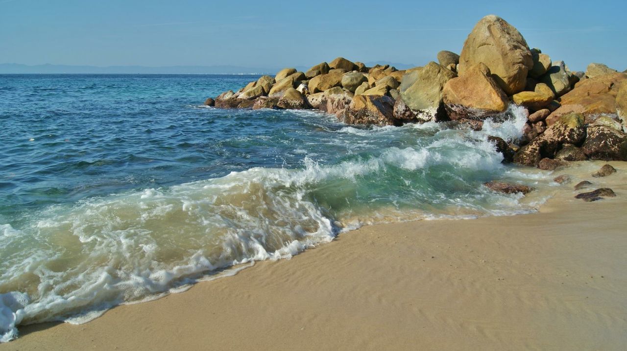 sea, beach, water, sand, shore, horizon over water, tranquil scene, scenics, tranquility, beauty in nature, wave, nature, clear sky, surf, coastline, idyllic, rock formation, blue, rock - object, sky