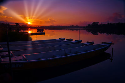 Silhouette boats moored in lake against sky during sunset