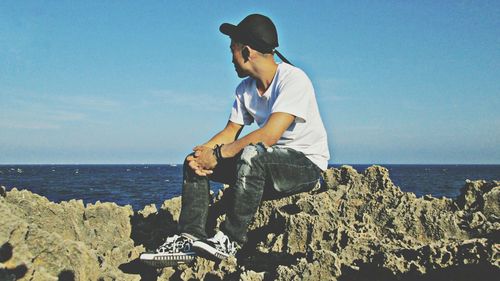 Woman sitting on beach against sky