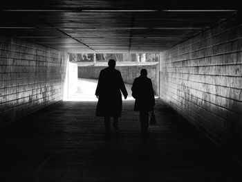 Full length rear view of silhouette people walking in tunnel